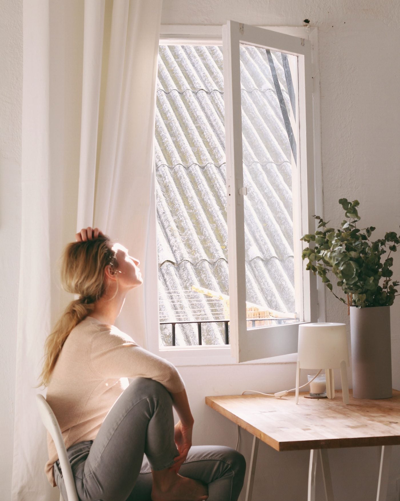 A woman sitting by a window, pausing