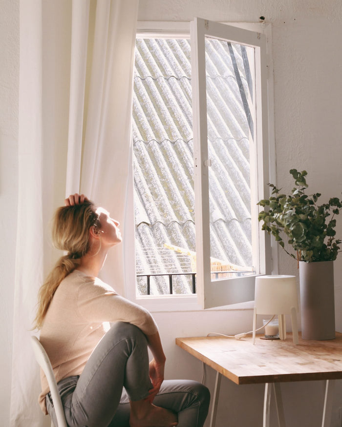 A woman sitting by a window, pausing